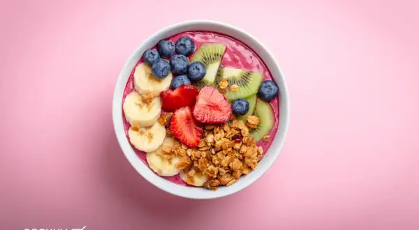 Eine bunte Acai Bowl mit Bananen, Erdbeeren, Blaubeeren und Kiwi, garniert mit Granola.