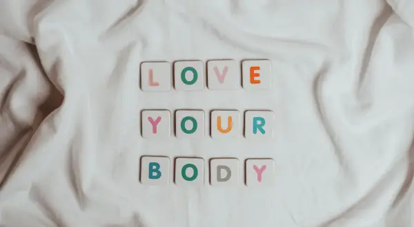 Kolorowe kafelki z literami układają się w napis "LOVE YOUR BODY". To piękna afirmacja, która przypomina o akceptacji siebie.