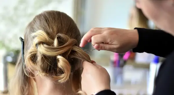 Fryzjerka tworzy elegancką fryzurę ślubną. Jej praca to sztuka, a kod zawodu fryzjer to opis jej talentu.