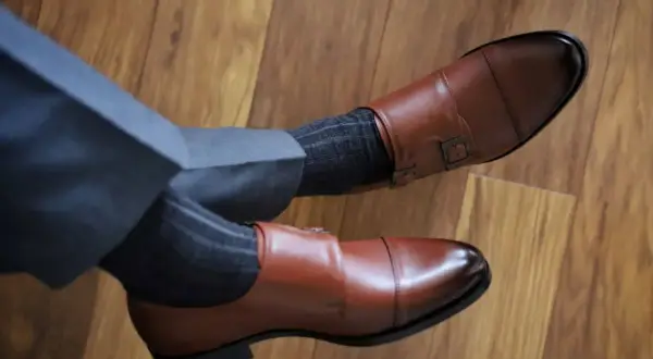 Granatowy garnitur, brązowe buty monk strap i grafitowe skarpetki w prążki tworzą elegancki zestaw.
