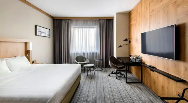 Nowoczesny pokój w jednym z **courtyard hotels Warsaw**. Duże łóżko, wygodne fotele i biurko przy oknie.