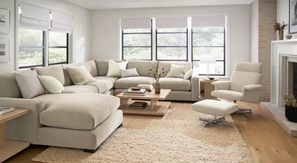 A large, neutral sectional couch is arranged in a cozy living room, showcasing different ways to arrange a sectional couch for optimal comfort and style.