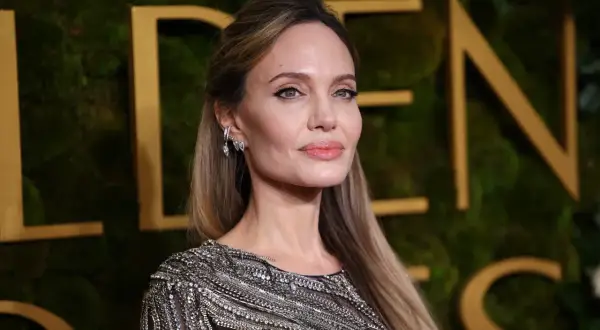Angelina Jolie, jedna z najbardziej znanych aktorek Hollywood, w błyszczącej kreacji na tle złotych liter.