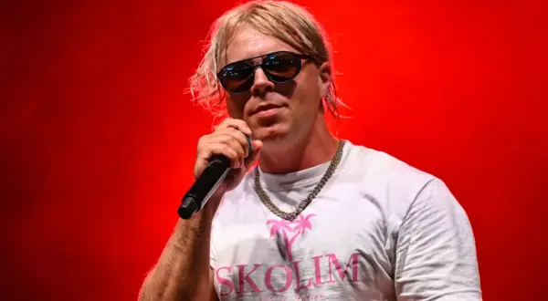 Artysta Skolim w okularach i białej koszulce z napisem "SKOLIM" na czerwonym tle. Zastanawiasz się, ile Skolim bierze za koncert?