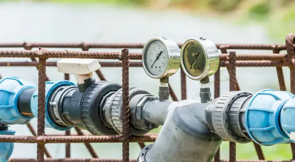 Manomètres sur tuyauterie grise et bleue, rouille sur la structure. Indique un possible problème adoucisseur d'eau.