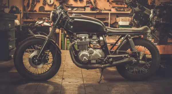 Czarny motocykl typu cafe racer w warsztacie, gotowy do sezonu.