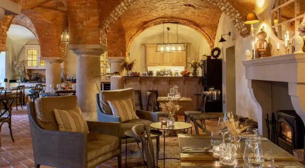 Wnętrze restauracji z ceglanymi łukami, kominkiem i stołami.