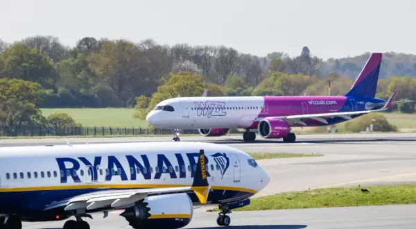 Dwa samoloty na płycie lotniska: jeden z napisem Ryanair, drugi z logo Wizzair. Którego wybierasz na wakacje?