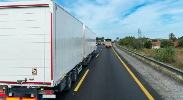 Deux semi-remorques blancs sur une autoroute, transportant chacun 44 tonnes de marchandises sous un ciel bleu.