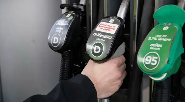 Hand håller dieselslang, funderar på dieseltillsats bra eller dåligt. Bredvid finns bensinslang.
