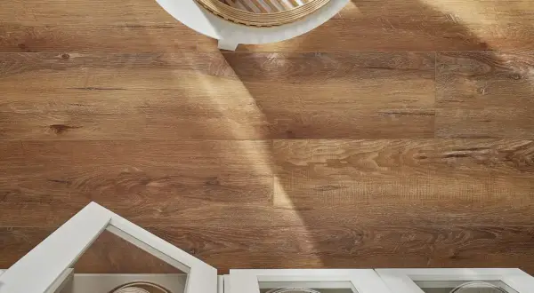 Drewnopodobne panele laminowane czy winylowe na podłodze, z widocznym fragmentem białej szafki i blatu.