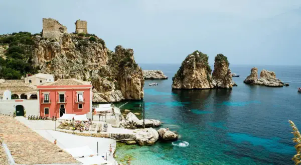 Scopri Castellammare del Golfo: case colorate, rovine antiche su scogliere rocciose e un mare cristallino con faraglioni.