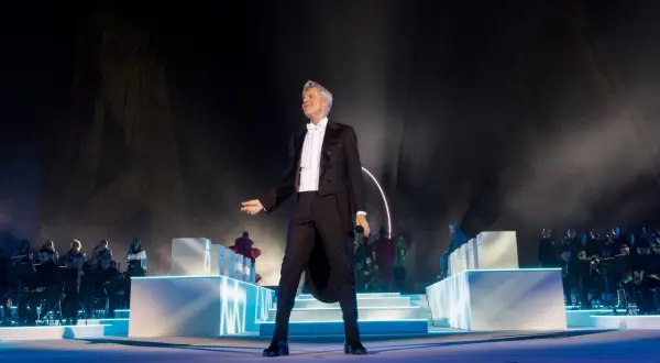 Claudio Baglioni in smoking, sul palco con orchestra e coristi, un momento iconico della sua biografia artistica.