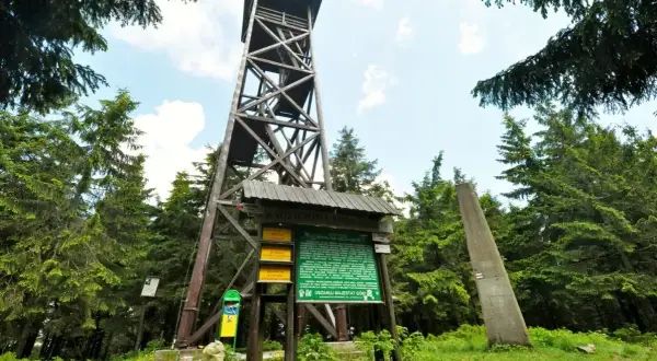 Drewniana wieża widokowa na Radziejowej. Obok tablica informacyjna i obelisk. To początek najkrótszego szlaku na Radziejową.