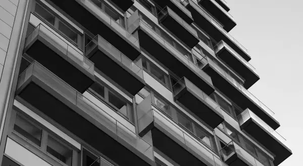 Nowoczesny budynek z balkonami, tworzący geometryczną kompozycję. Widok z dołu, podkreślający architekturę. WM rejestracja.