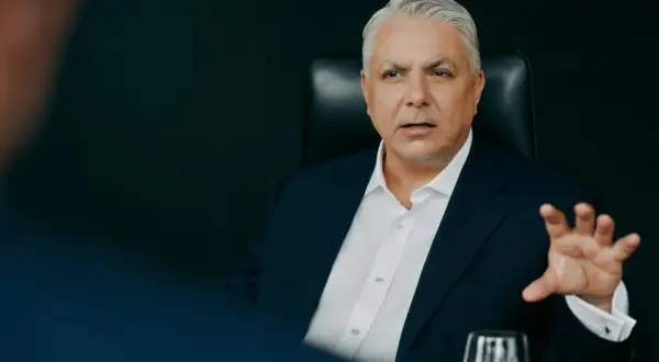 Mężczyzna w garniturze, członek Erste Group, gestykuluje podczas rozmowy.