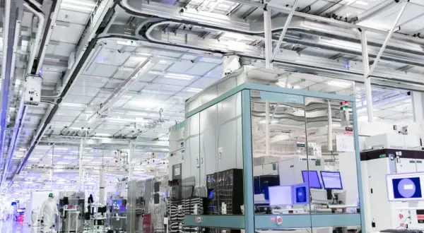 Czysty, nowoczesny zakład produkcyjny, gdzie powstają technologie dla największych firm IT na świecie. W tle widać linie produkcyjne i systemy transportowe.