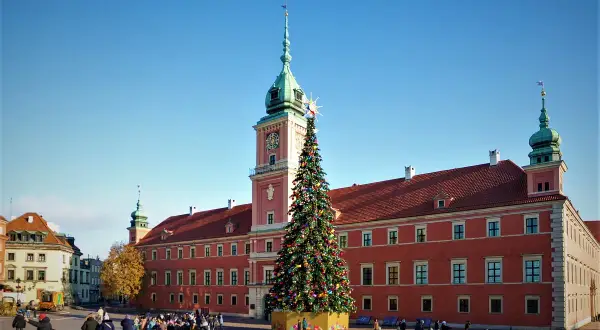 Wspaniała choinka w Warszawie przed Zamkiem Królewskim, ozdobiona kolorowymi lampkami i bombkami, przyciąga tłumy spacerowiczów.