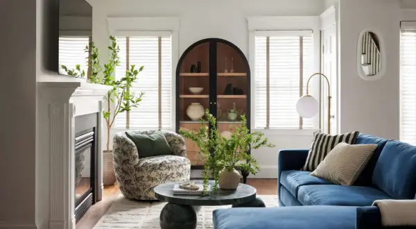 A round coffee table decor features a vase with greenery and a beaded strand, adding a natural touch to the living room.