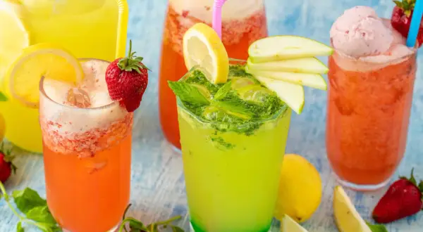 Färgglada alkoholfria drinkar med frukt och is. En grön drink med mynta och äpple, en rosa med jordgubbar och glass, samt en orange.