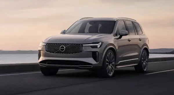 Szary Volvo XC90 w ruchu, z pięknym zachodem słońca w tle. Wiele osób szuka volvo xc90 opinie przed zakupem.