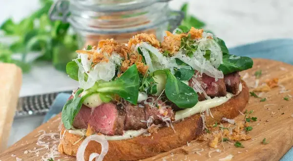 En läcker steak sandwich med mört kött, krispig sallad, lök och parmesan på rostat bröd.