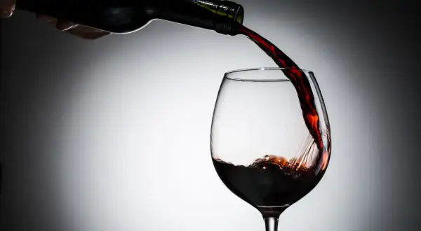 Czerwone wino nalewane do kieliszka. Czy czerwone wino jest zdrowe? Dyskusja trwa, ale jego piękny kolor zachwyca.