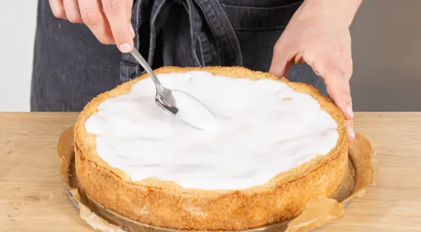 Landfrauen-Rezept: Ein goldbrauner Apfelkuchen wird mit einem Löffel mit süßem Guss überzogen.