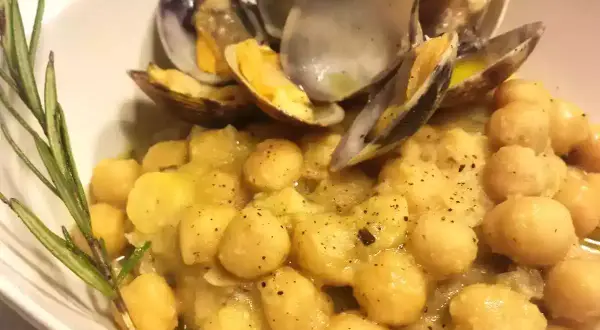 Un piatto invitante di ceci e vongole, condito con erbe aromatiche e pepe nero.