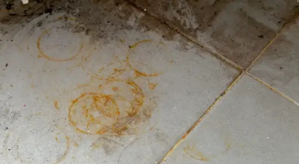 Rdzawe plamy na granicie tworzą wzory, jakby ktoś zostawił ślady po kubkach.