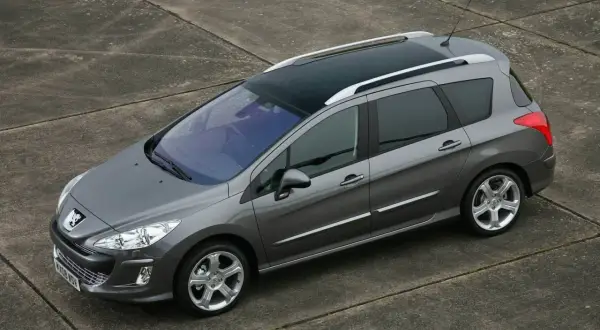 Szary Peugeot 308 1.6 HDI kombi z panoramicznym dachem stoi na betonowej nawierzchni.