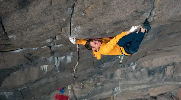 Ein Kletterer meistert eine anspruchsvolle **offwidth climbing** Route, seine Hände greifen fest in den Fels.