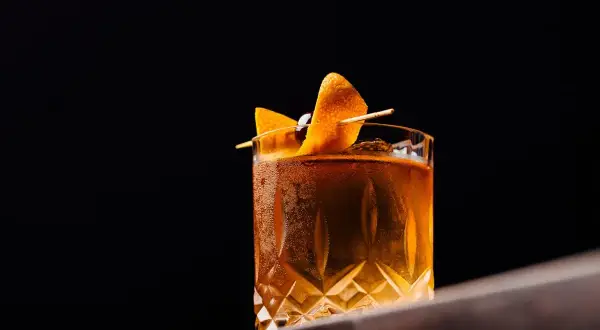 Elegancki drink z pomarańczą i wiśnią, idealny do degustacji. Czy to klasyczny Old Fashioned z dodatkiem angostura?