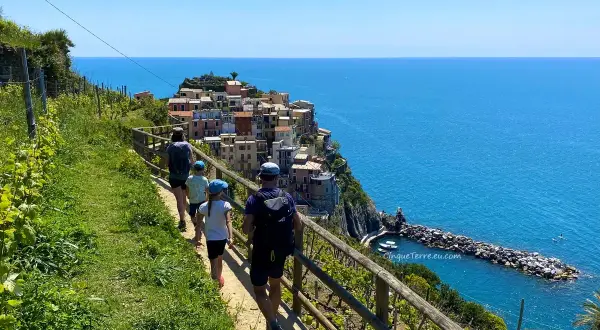 Familj på en vacker cinque terre vandring längs kusten med färgglada hus och blått hav.