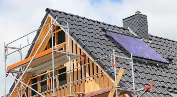 Gerüst am Dach eines Hauses, das saniert wird. Solarkollektoren sind installiert.