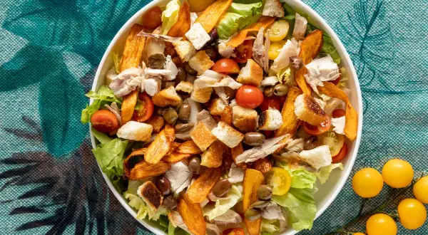 Insalata di pollo ricca con crostini dorati, pomodorini succosi, olive e patate dolci croccanti. Un piatto gustoso e colorato.