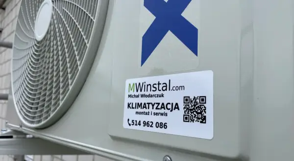 Zewnętrzna jednostka klimatyzatora z naklejką firmy MWinstal.com.