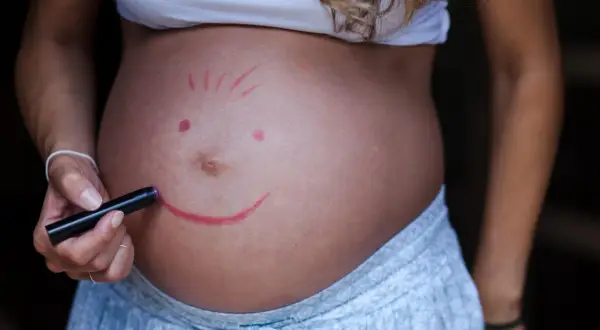 Brzuch ciężarnej z namalowaną buźką. Czy dziecko w brzuchu czuje, że jest niechciane? Nie, ta buźka mówi "kocham Cię".