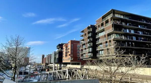 Moderne Gebäude mit Balkonen säumen das Wasser, wo Boote liegen. Die Magellan Terrassen bieten einen Blick auf die Hafencity.