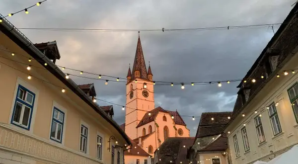 En charmig europeisk stad med en kyrktorn i bakgrunden, kantad av hus och ljusslingor. Perfekt för en resa till billigaste landet i Europa.