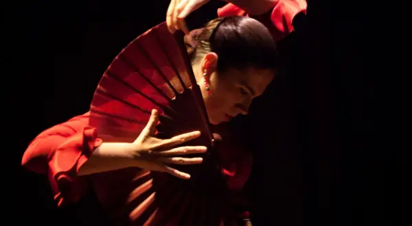 Bailarina de flamenco con un abanico rojo, evocando la pasión de la guajira.