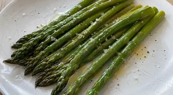 En tallrik med perfekt kokt sparris, lätt oljad och strödd med flingsalt och peppar. En enkel och god rätt att koka sparris till.