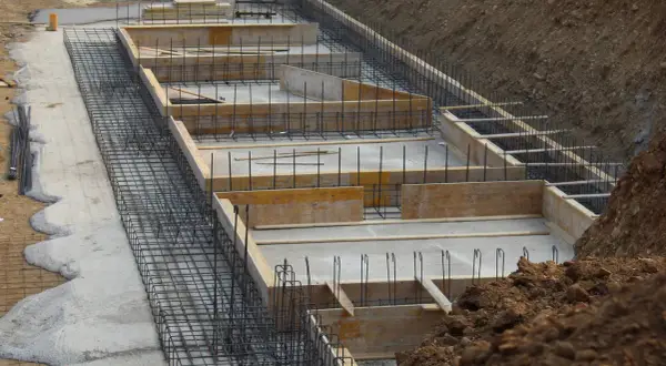 Szkielet zbrojeniowy i szalunki drewniane czekają na beton. Tak wygląda budowa fundamentów krok po kroku.