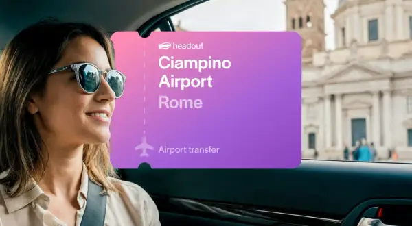 Kobieta w okularach przeciwsłonecznych jedzie samochodem w Rzymie. Na ekranie widnieje napis "Ciampino Airport Rome".
