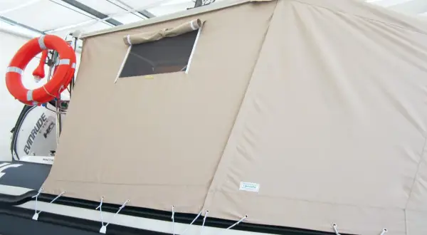Tenda campeggio nautico su gommone, con oblò e salvagente arancione.