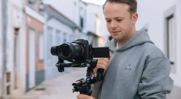 Mężczyzna z kamerą Sony Alpha 7 na stabilizatorze DJI Ronin S2. Zastanawiasz się, który aparat fotograficzny wybrać?