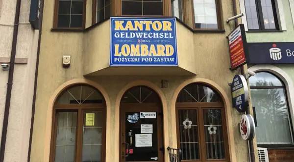 Elewacja budynku z szyldem "KANTOR GELDWECHSEL LOMBARD POŻYCZKI POD ZASTAW".