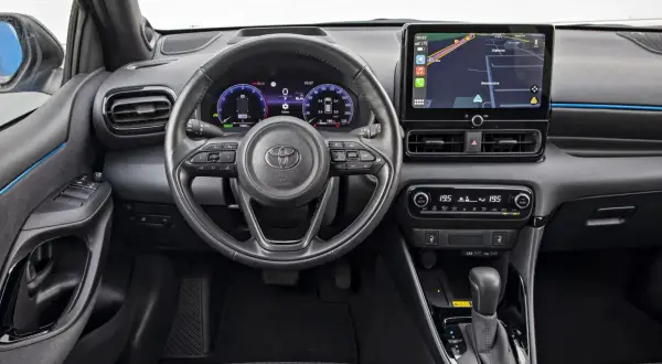 Wnętrze Toyoty Yaris Hybrid. Nowoczesny kokpit z ekranem nawigacji i cyfrowymi zegarami. Sprawdź atrakcyjną toyota yaris hybrid cena.