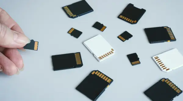 Dłoń trzyma kartę pamięci, obok leżą różne karty SD i microSD. Jaka karta pamięci do aparatu będzie najlepsza?
