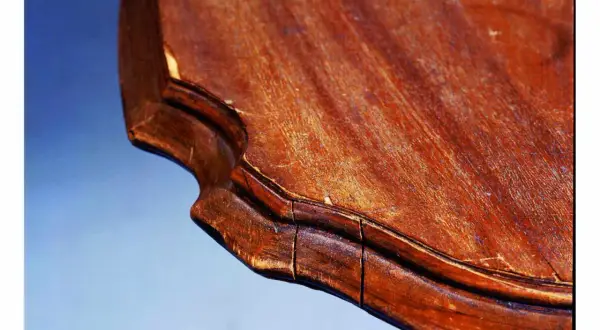 Gros plan sur le bord d'une table en bois qui se fissure, révélant les signes du temps et de l'usure.